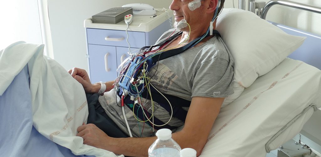 Photo d'un patient équipé du dispositif de polysomnographie et installé dans sa chambre d'hospitalisation