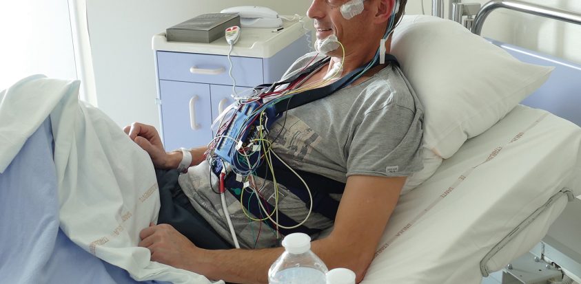 Photo d'un patient équipé du dispositif de polysomnographie et installé dans sa chambre d'hospitalisation